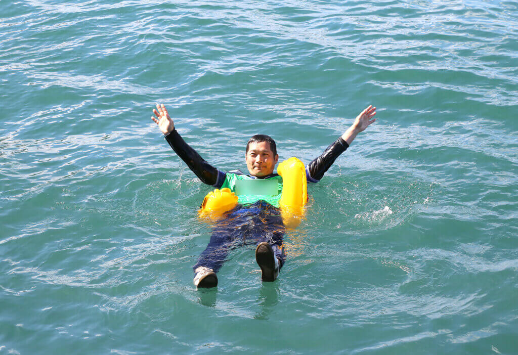 訓練でライフジャケットを付けた人が水面で浮いている様子